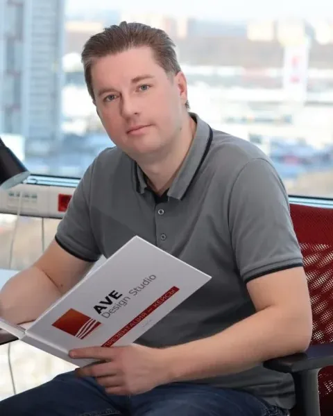 Александр Евстигнеев, основатель AVE Design Studio, в офисе студии с буклетом AVE Design Studio